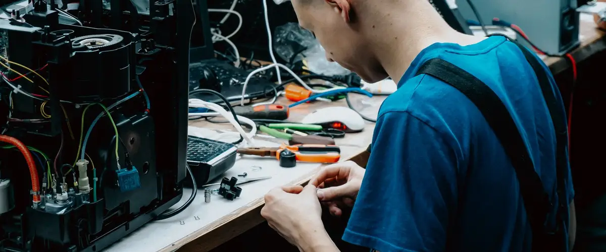 Techniker arbeitet konzentriert an einem geöffneten Gerät in der Werkstatt (Symbolbild)