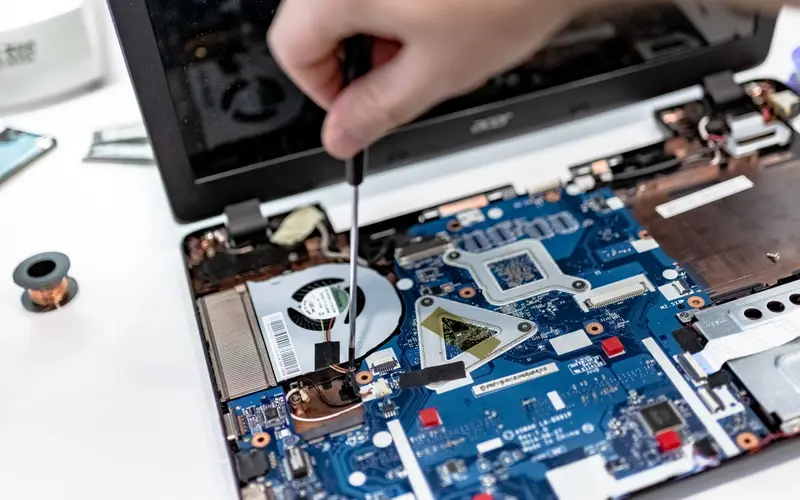 Notebook-Mainboard wird mit Schraubendreher repariert (Symbolbild)